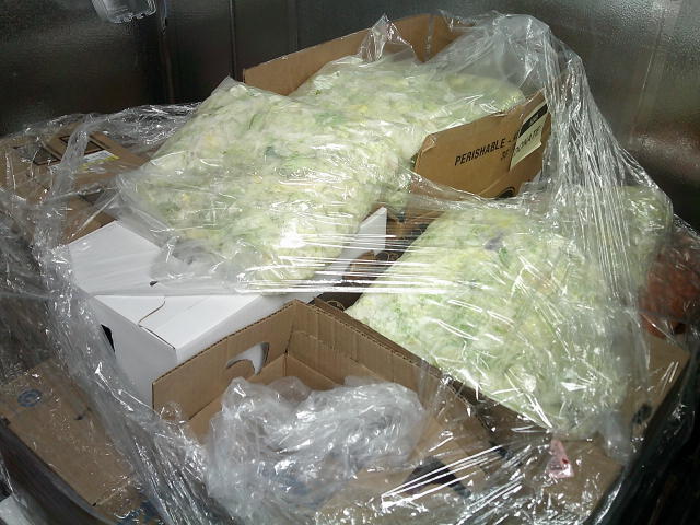 Boxes of lettuce surrounded by plastic wrap.